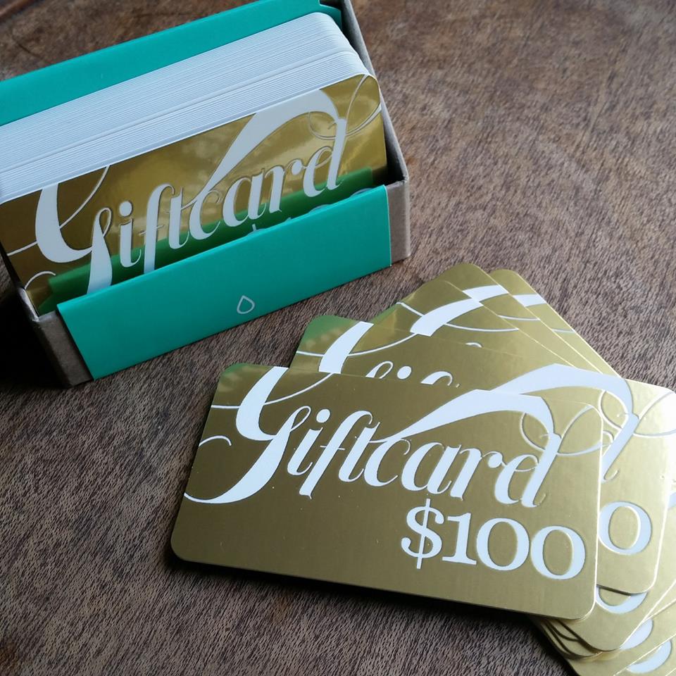 Gold foil embossed gift cards in a box, with several stacked next to it.